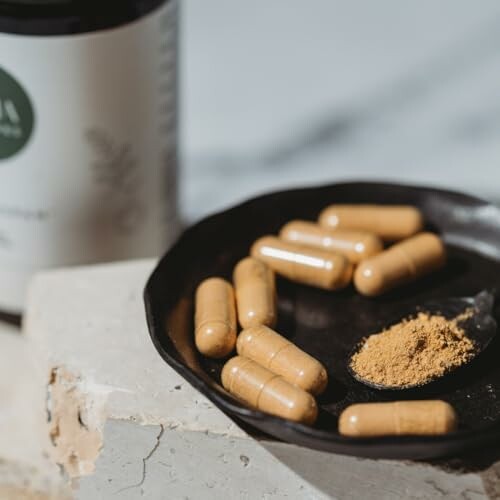Herbal supplement capsules and powder on a plate.