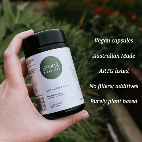 Hand holding a bottle of vegan capsules with product highlights.